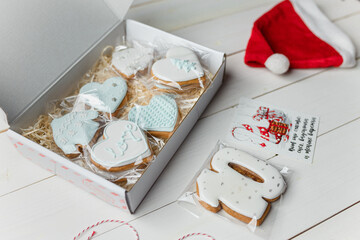 Christmas cookies. Number ten, hearts and sweaters shapes. Winter pastry on white wooden background. Santa hat. Inscription on card: Happiness is snow, sweets and warm mittens.