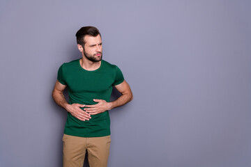 Portrait of frustrated man eat something wrong suffer stomach ache gastritis syndrome wear green...
