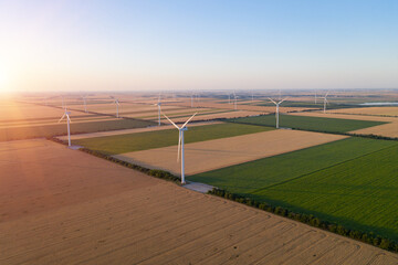 Sunset over the windmills. Wind turbines over fields of wheat and sunflowers