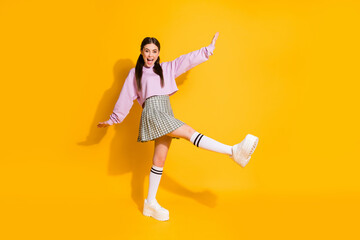 Full length photo of candid pretty youth teenager girl enjoy spring weekend rest relax holiday scream raise legs hands wear good look clothes isolated over shine color background