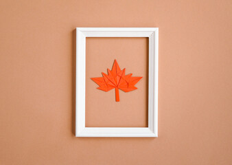 Frame with decorative paper leaves on a beige background. Greeting card, autumn season, thanksgiving. Minimum concept, autumn composition.  Top view,  flat lay, copy space