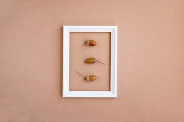Frame with acorns on a beige background. Greeting card, autumn season, thanksgiving. Minimal concept, autumn composition. Top view, flat lay, copy space
