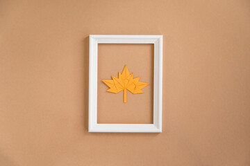 Frame with maple leaf on a beige background. Greeting card, autumn season, thanksgiving. Minimal concept, autumn composition. Top view, flat lay, copy space