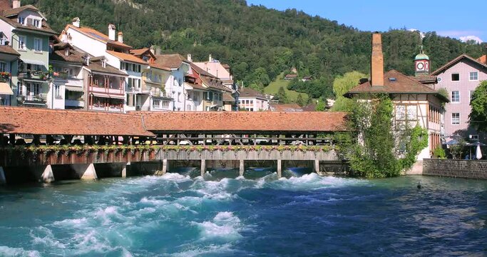 Old, historical wooden bridge in Thun over Aare river, turquoise water, cityscape of alpine town. Switzerland
