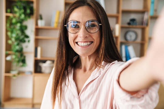 Image of joyful adult businesswoman smiling while taking selfie photo