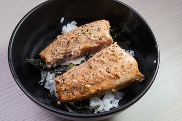A bowl of grilled salmon on top of rice.