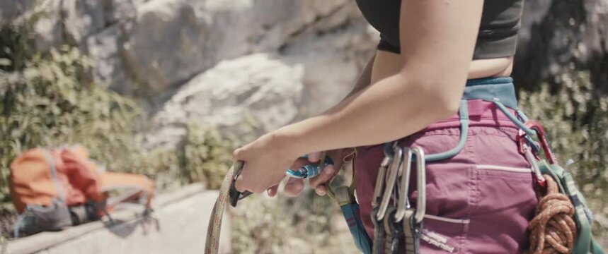 Female paralympic climber woman athlete missing fingers on hand attach carabiner rope before rock climb outdoors lifestyle sport in nature unrecognizable close up