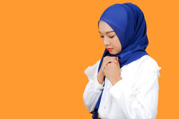 Muslim woman wearing hijab head scarf hold her hands for praying.