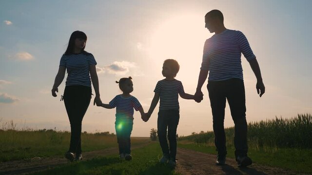 Happy family. Lovely couple with kids strolling at sunset in the evening around the field. The concept is the teamwork of hiking, active lifestyle, parenting.
