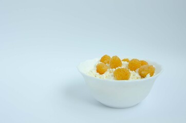 Cheese in a white plate and yellow raspberries. Raspberries and cottage cheese