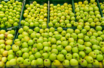 fruits, harvest, food and sale concept - green apples at grocery store or market