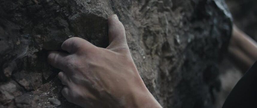 Female paralympic climber woman athlete missing fingers on left hand hold grip with chalk on stone rock climb ascends outdoors lifestyle sport in nature unrecognizable close up slow motion