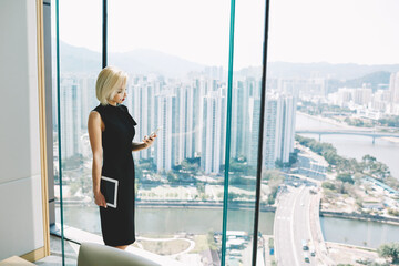 Young woman successful economist of big trading real estate company is checking e-mail on cell...