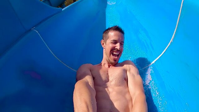 Slow Motion Shot Of A 40s Caucasian Adult Man Going Down The Slide Of A Water Park.