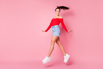 Full body profile photo of pretty funky lady jumping high excited walking sale shopping wear red open shoulders shirt mini denim skirt shoes isolated pastel pink color background