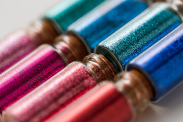 party, decoration and holidays concept - close up of different color glitters in small glass...
