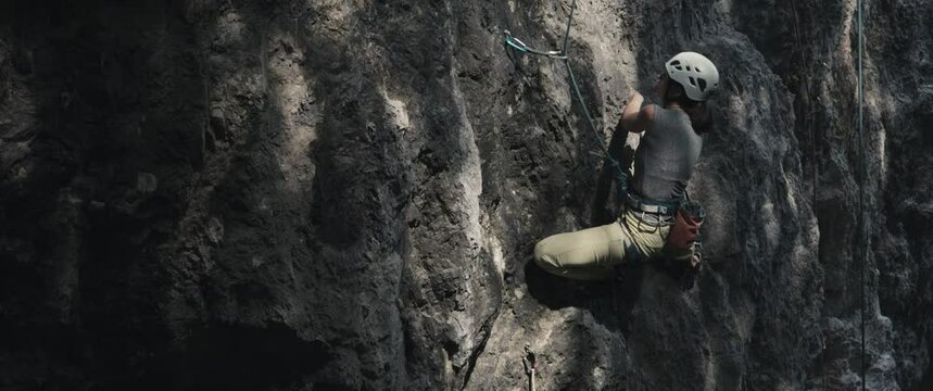 Female climber woman athlete wear helmet struggle rock climb ascend dark stone outdoors lifestyle sport in nature