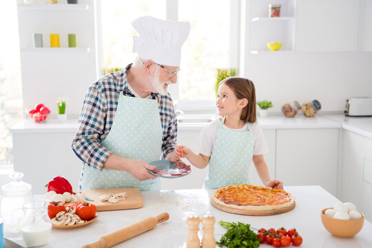 Portrait of his he her she nice friendly cheerful grey-haired grandparent grandchild learning cooking fresh homemade delicious dish pizza recipe workshop in modern light white interior kitchen house