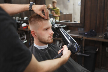 Close up of a man having his hair blow dried by professional barber