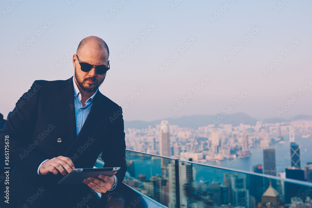 Poster confident executive manager in stylish sunglasses browsing internet website with financial news on d