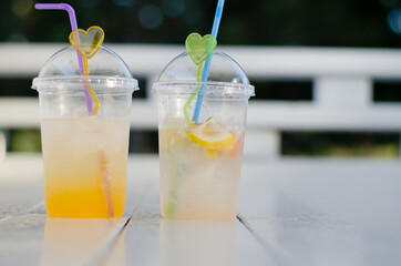 Two glasses of juice on a white wooden table. Cold drinks. Orange juice and mojito.