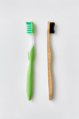 dental care, sustainability and eco living concept - wooden and plastic toothbrush on white...