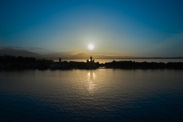 Naklejka premium Sunrise over Sirmione, Lake Garda Italy. Blue sky, trail from the sun on the water. Aerial view