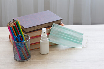 books, pencils, face shield and hand sanitizer are on the table