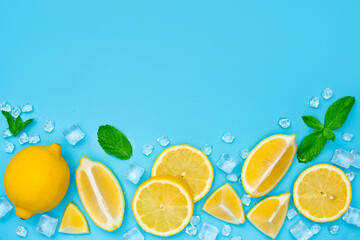 Lemon slices with ice and mint on blue background with copy space. Lemonade or mojito set top view.