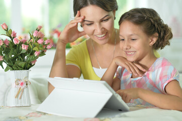 Happy mother and daughter using tablet together at home
