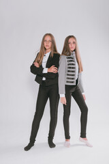 Fototapeta premium Two cute girls schoolgirls in a trendy school uniform on a white background. School fashion. Children's school fashion clothes