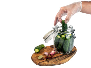 Marinated, pickled cucumbers in a glass jar on a wooden board isolated on white
