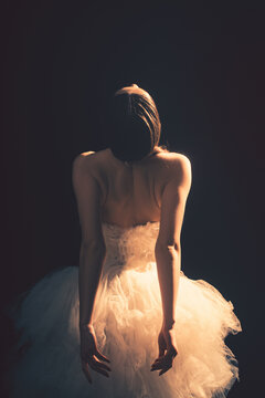 Young beautiful ballet dancer is posing in studio, view back.