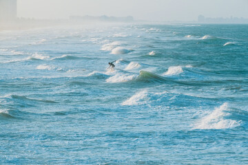 Naklejka premium Sea landscape with waves and surfer. A surfer trains.