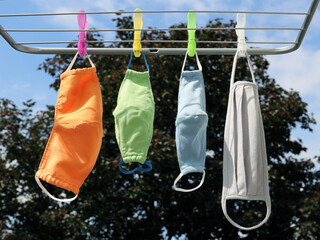 Bright colourful handmade textile face masks for the whole family for adults and kids hang on a...