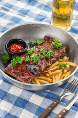 grilled pork ribs with french fries and glass of beer on fabric napkin