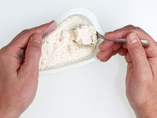 Old man eats cottage cheese from a plastic box