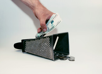 a man’s hand rubs a banknote, and iron coins lie below
