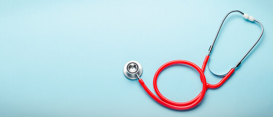 Red stethoscope on blue color background. Concept of medicine and health care. Top view copy space for text. Long web banner
