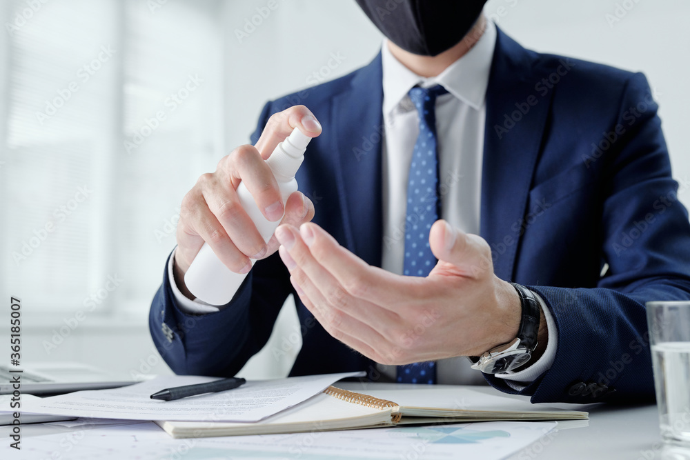 Poster close-up of unrecognizable businessman sitting at desk with notepad and papers and cleaning hands wi