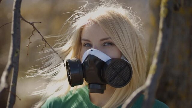 Blonde woman in respirator face mask on warm background