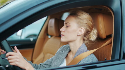 Closeup businesswoman sitting behind steering wheel. Woman dancing in car