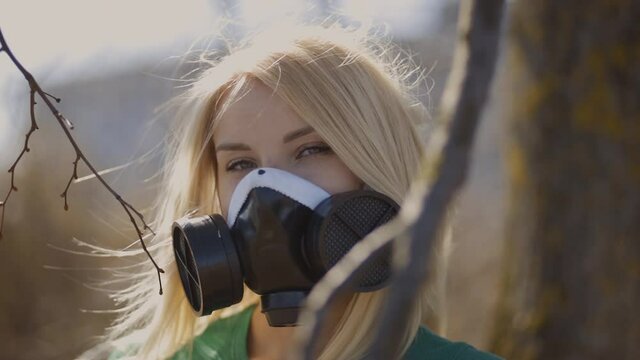 Blonde woman in respirator face mask on warm background