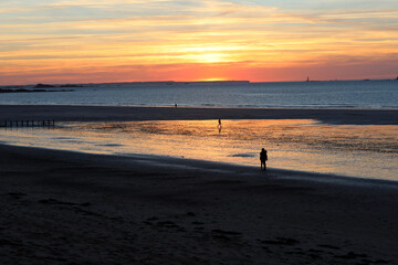 Romantic walk of people before sunset on the picturesque beach of Saint Malo. Brittany, France