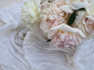 Obraz premium Bouquet of white peonies with fabric on a light background, closeup, top view. Romantic flower image for cover design and printing, copy space.