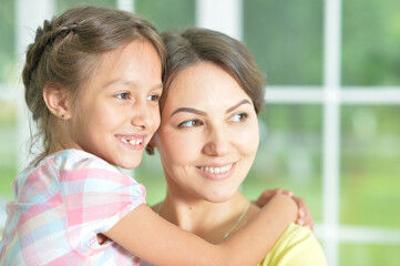 Portrait of a charming little girl hugging with mom at home