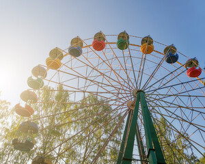 Multi-colored Ferris wheel in the park in a sunny summer day.
