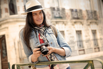 Fototapeta na wymiar Woman wearing hat, taking pictures in european town during vacation