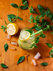 Refreshing summer detox lemonade with cucumber, lemon and mint in a glass on a wooden table top view