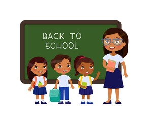 Teacher greeting pupils in classroom flat vector illustration. Boys and girls dressed in school uniform and female teacher pointing at blackboard cartoon characters. Primary students back to school